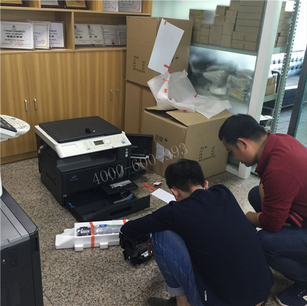师傅在安装柯尼卡美能达206复印机，客户在旁边咨询复印机的相关问题